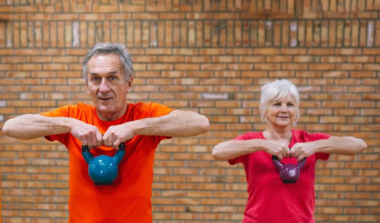 En kvinna och en man som gör träning med kettlebell 