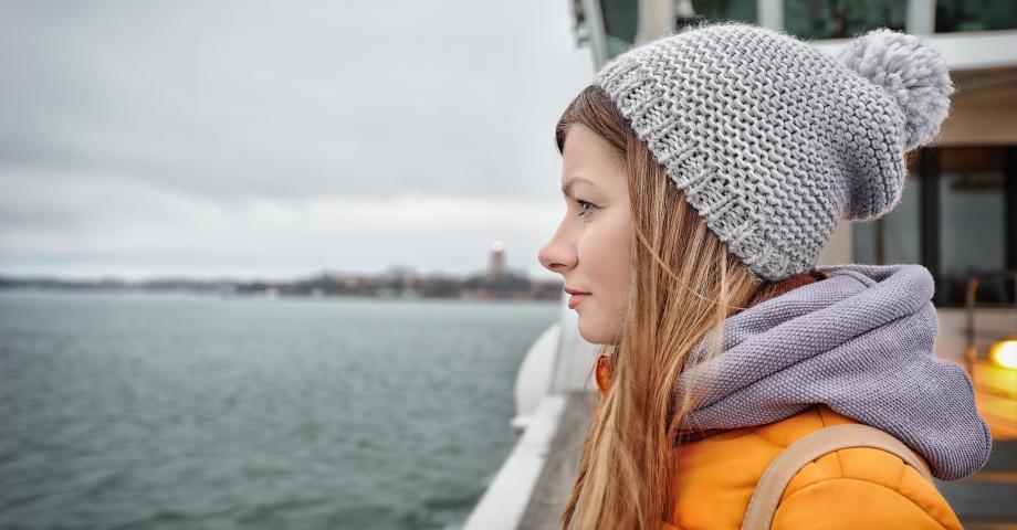 Nainen keltaisessa takissa katselee laivan kannelta merelle