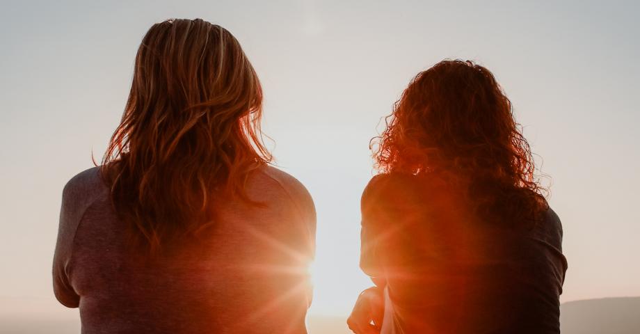 Kahden naisen siluetti ja auringonlasku.