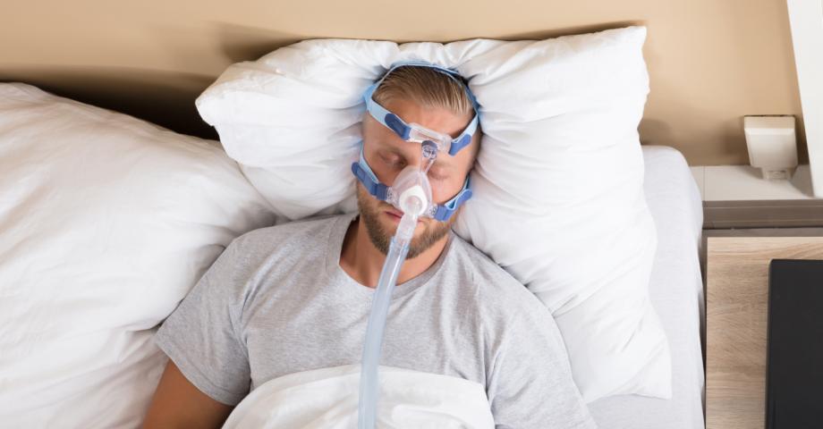 Den sovande mannen använder en CPAP-apparat för att behandla sömnapné