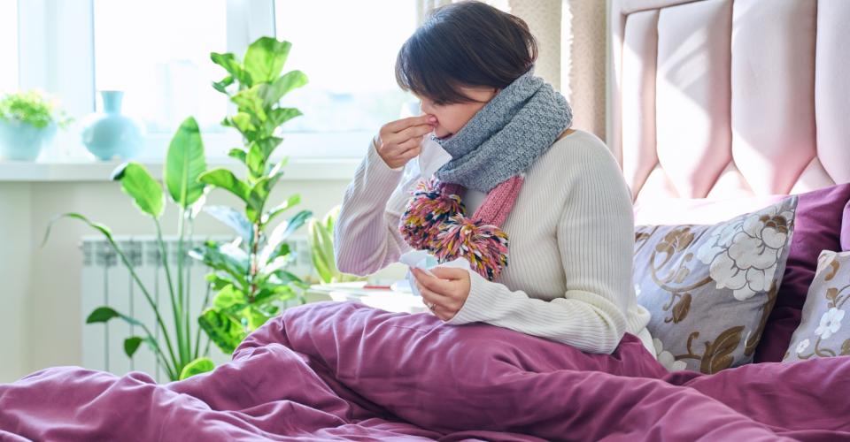 Flu patient sitting on a bed sneezing.