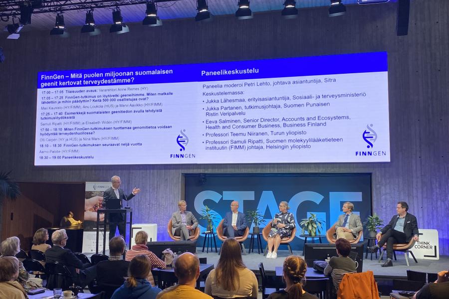 Paneldebatten börjar, på scenen finns moderatorn och fem panelister, i bakgrunden finns Tiedekulman STAGE-text och programbild.